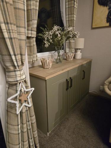 a cabinet with a window with a vase of flowers at Lynmar retreat No 35 in Dornoch