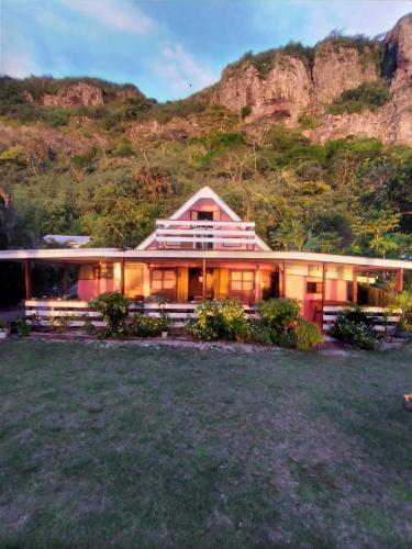 a large house with a mountain in the background at Maupiti Authentique in Te-Fare-Arii