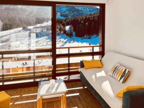 ein Wohnzimmer mit Couch und großem Fenster in der Unterkunft Le Haut Griou aux pieds sur les pistes, 8pers, cœur station, Le Lioran in Laveissière
