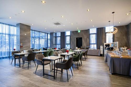 a restaurant with tables and chairs and windows at The Western Busan Hotel By STAYNEO in Busan