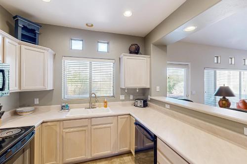 La cuisine est équipée de placards blancs, d'un évier et de fenêtres. dans l'établissement Vistoso Resort Casita #127, à Tortolita