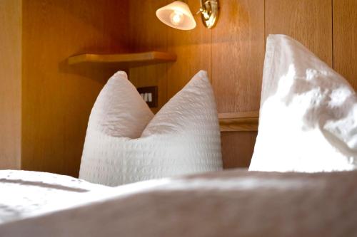 a white bed with white pillows on it at Haus Peer Burgeis in Burgusio