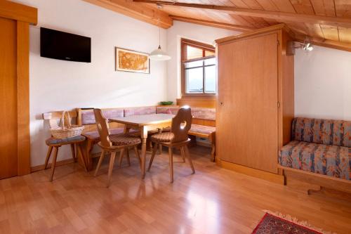 a dining room with a table and chairs and a couch at Haus Peer Burgeis in Burgusio