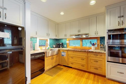 a kitchen with white cabinets and wooden floors at Mad River Masterpiece in Irasville
