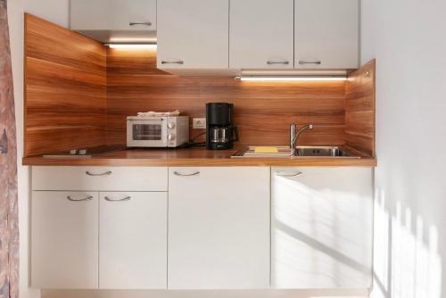a kitchen with white cabinets and a microwave at Haus Peer Burgeis in Burgusio