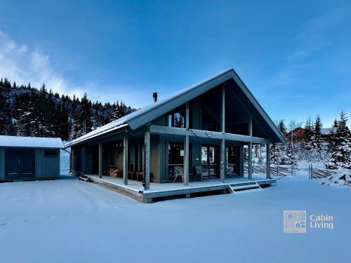 a house in the snow with snow covered ground at Modern cabin Skeikampen with ski-in out cross country trails & great view in Aulstad