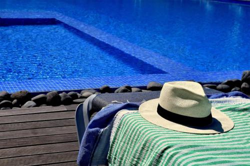 a hat sitting on a towel next to a swimming pool at Piscina fantástica no centro da cidade! in Funchal