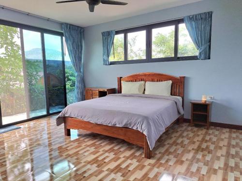 a bedroom with a large bed with windows at Seaview Eagles Nest Apartment 3 in Nai Harn Beach