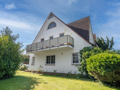 a white house with a gambrel roof and a balcony at Abenteuer Zingst, FW Kormoran 10 in Zingst