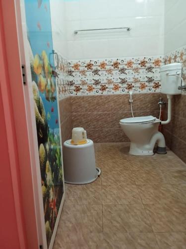 a bathroom with a toilet and a painting on the wall at Paradise Forest Resort in Puducherry
