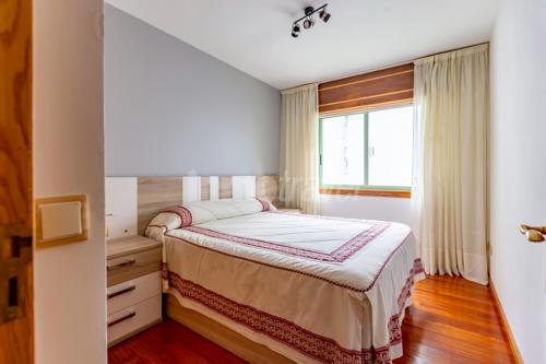 a bedroom with a large bed with a window at Apartamento a pie de playa in Portonovo