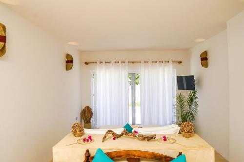 a room with a table and a large window at Aquamarina Hotel in Jambiani