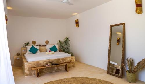 a bedroom with a large bed and a mirror at Aquamarina Hotel in Jambiani