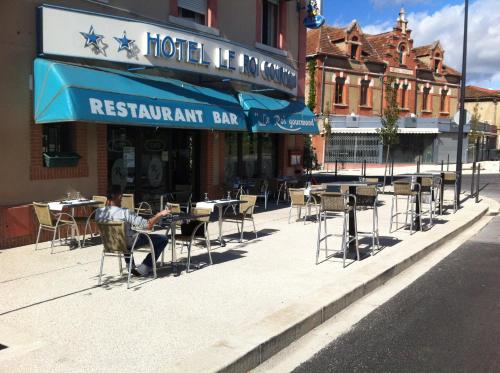 a man sitting at a table in front of a restaurant at Hôtel Le Roi Gourmand in Pamiers