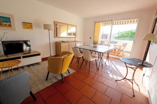 un salon avec une table, des chaises et une télévision dans l'établissement Superbe T3 pour 6 personnes, résidence calme avec piscine, à Cassis