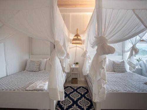 a bedroom with two beds with white curtains at The Seahouse Antigua SEAFRONT in Bats Cave