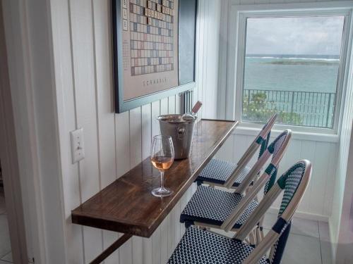 a table with a glass of wine and two chairs at The Seahouse Antigua SEAFRONT in Bats Cave