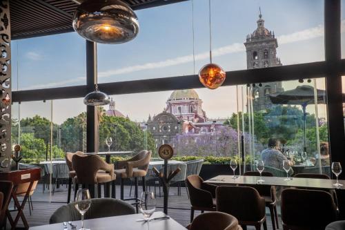 a restaurant with tables and chairs and a view of a building at voco Royalty Puebla Downtown by IHG in Puebla