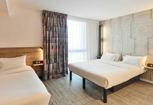 a hotel room with two beds and a window at B&B HOTEL Marne-la-Vallée Val d'Europe in Serris