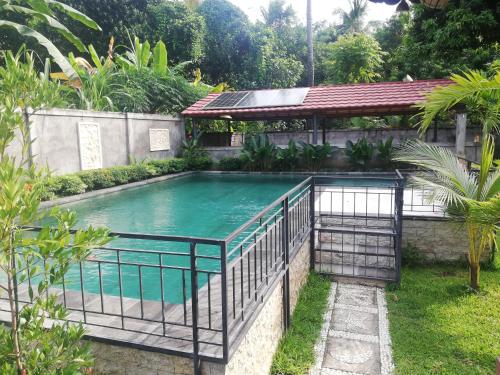 a swimming pool in a garden with a fence around it at Villa MaLiNa in Tejakula