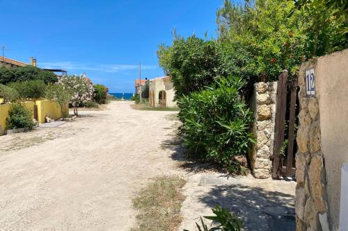 a dirt road with a fence and trees at Casa Perassi in Putzu Idu
