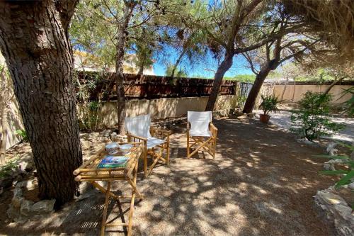 a patio with two chairs and a table under a tree at Casa Perassi in Putzu Idu