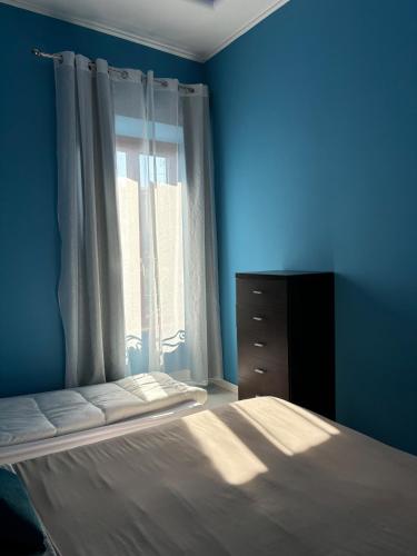 a blue bedroom with a bed and a window at Vistadamare in Nettuno