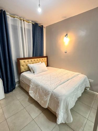 a bedroom with a large bed with blue curtains at Residence Next Door Coral Mega in Kiambu