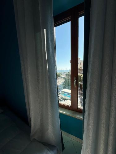 a bedroom with a window with a view of a city at Vistadamare in Nettuno