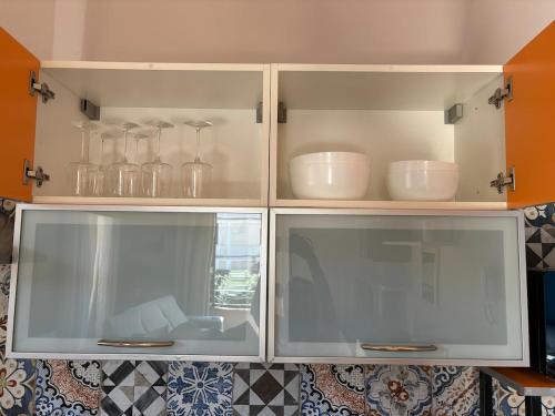 a kitchen cabinet with glass doors with dishes on it at Vistadamare in Nettuno