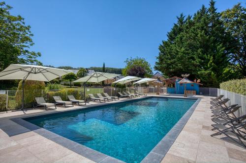 une piscine avec chaises et parasols dans l'établissement Le Domaine des Crouquets Sarlat, à Jayac