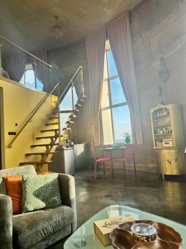a living room with a staircase and a couch and a table at Watertorenhotel WADHOOG in Sint Jacobiparochie