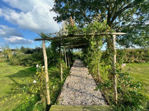 a garden arch with a pathway in a field at Watertorenhotel WADHOOG in Sint Jacobiparochie