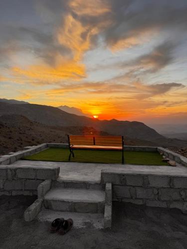 a bench sitting on top of a hill with the sunset at Suhail Star Guest House in Misfāh