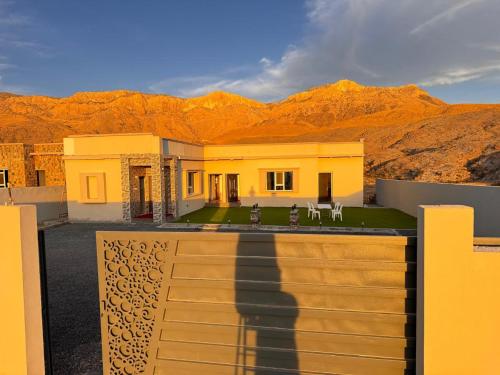 a house in the desert with mountains in the background at Suhail Star Guest House in Misfāh
