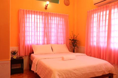 1 dormitorio con 2 camas y cortinas rosas en Eco-Home Siem Reap Homestay, en Siem Reap