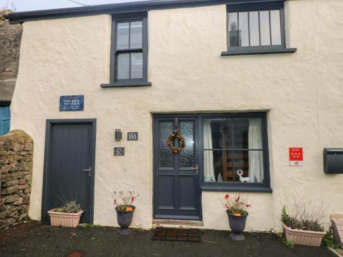 a white house with a blue door and windows at Stable Cottage in Pembroke