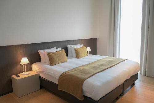 a large bed in a bedroom with two lamps at Martin's Rentmeesterij in Bilzen