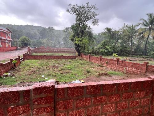 a brick wall next to a field with trees at Shree Balaji Natures lap villa in Mirya