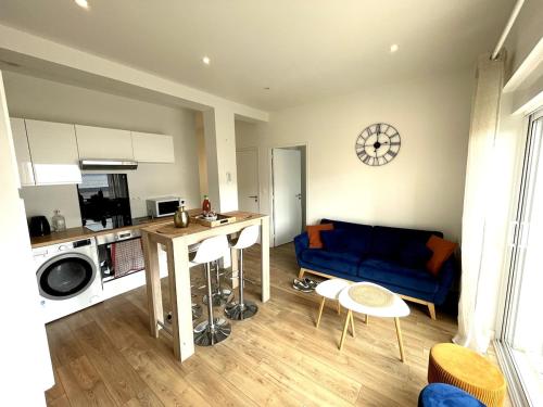 un salon avec un canapé bleu et une cuisine dans l'établissement Le Clemenceau - centre ville, proche gare et commerces, à Saint-Brieuc