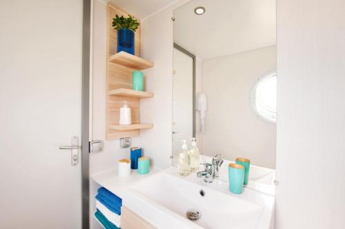 une salle de bain avec un lavabo et un miroir dans l'établissement Domaine Résidentiel de Plein Air Le Vieux Moulin, à Erquy