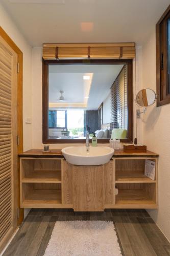 a bathroom with a sink and a large mirror at The Rock Samui Beachfront Villas - Sha Plus Hotel in Lamai