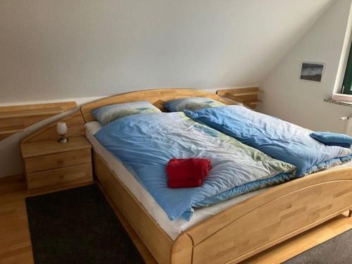 a large wooden bed with a red pillow on it at LeaID in Idstedt