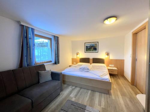a bedroom with a bed and a couch at Holiday Home Wallner by Interhome in Fusch an der Glocknerstraße