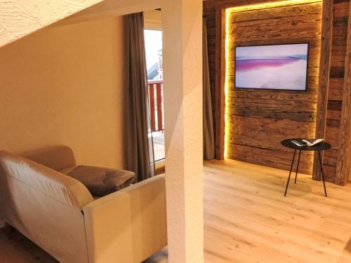 a living room with a couch and a television on a wall at Apartment Wiedersehn Dachgeschoss by Interhome in Grächen