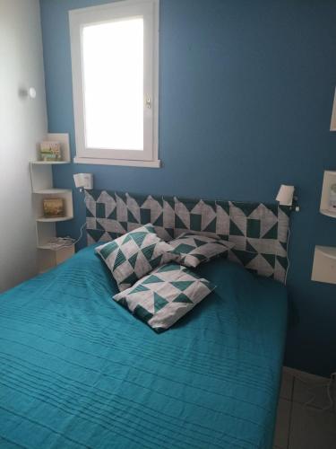 une chambre bleue avec un lit avec deux oreillers dans l'établissement 5 pers - balcon - proche mer, à Port-la-Nouvelle