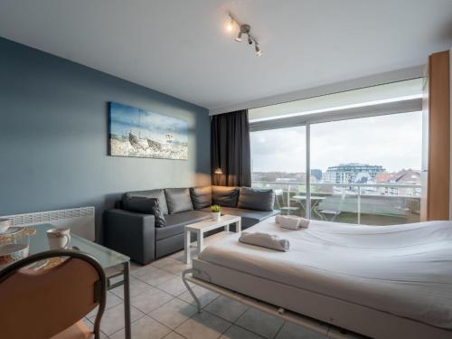 a bedroom with a bed and a couch and a window at Studio Studio 502 by Interhome in Bredene