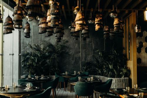 a restaurant with tables and chairs and potted plants at Palmaïa The House of AïA All Inclusive Wellness Resort in Playa del Carmen