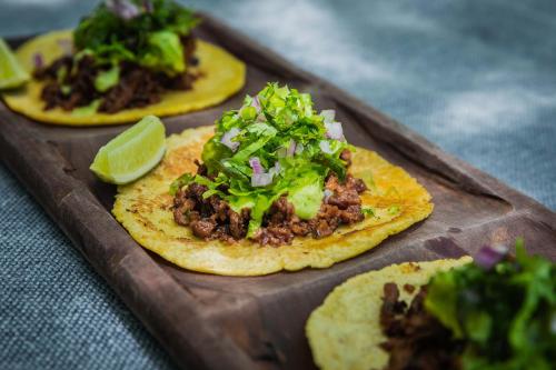 three tacos with meat and lettuce on a cutting board at Palmaïa The House of AïA All Inclusive Wellness Resort in Playa del Carmen