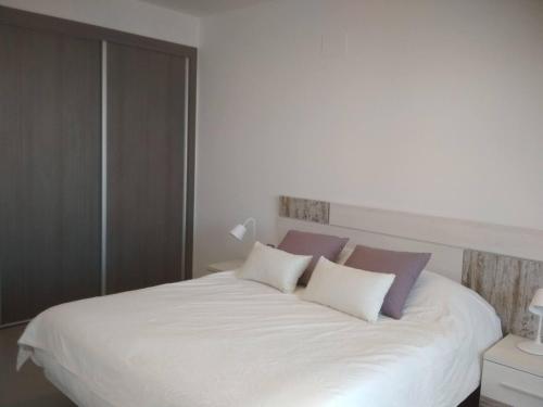 - une chambre avec un lit blanc et des oreillers violets dans l'établissement Moderno apartamento con piscina R35 by Novadesta, à Arenales del Sol